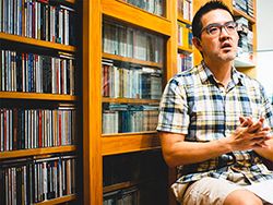焦元溥坐於房間CD牆一側,解說他的專輯收藏