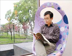 王文華坐在埔里鎮立圖書館窗邊閱讀，享受愜意時光。